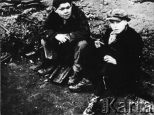 Dwaj chłopcy siedzą na ziemi, prawdopodobnie są to dzieci z grupy, która opuściła ZSRR z wojskami Andersa.