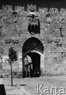 Arab na osiołku wyjeżdża przez miejską bramę.