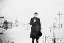 Młody mężczyzna zesłany na Syberię stoi wśród krzyży na cmentarzu.