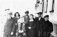 Polacy przebywający na zesłaniu stoją na ulicy przed domem, w kt&oacute;rym mieszkali, w środku stoi Stanisława Gortyńska.